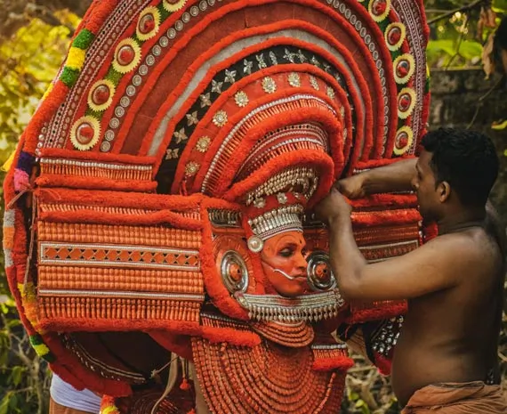 Personne décorée d'une coiffe orange traditionnelle de la région de Kerala en Inde du Nord