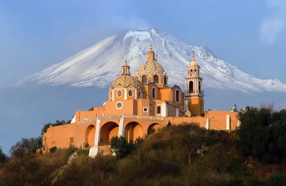 Sanctuaire orange avec des coupoles sur fond de montagne enneigée au Mexique