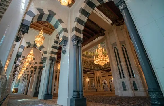 Intérieur de la grande mosquée avec des colonnades à rayures et lustres dorés